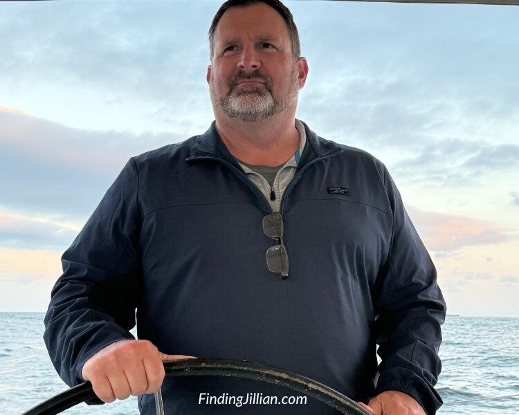 Man steering boat at sunset